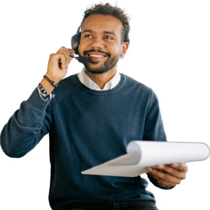 A smiling man with a headset holding a pen and clipboard, dressed in a dark sweater, looking off to the side as he reviews weight goals.